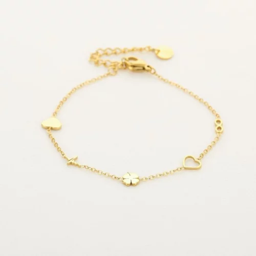 Goudkleurige schakelarmband met hartjes, klavertje vier en infinitysymbool op een lichte ondergrond.